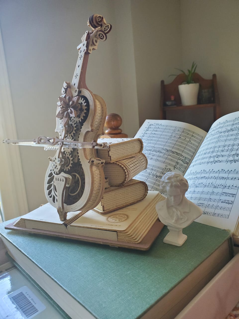 Decorative violin model beside sheet music and a composer's bust