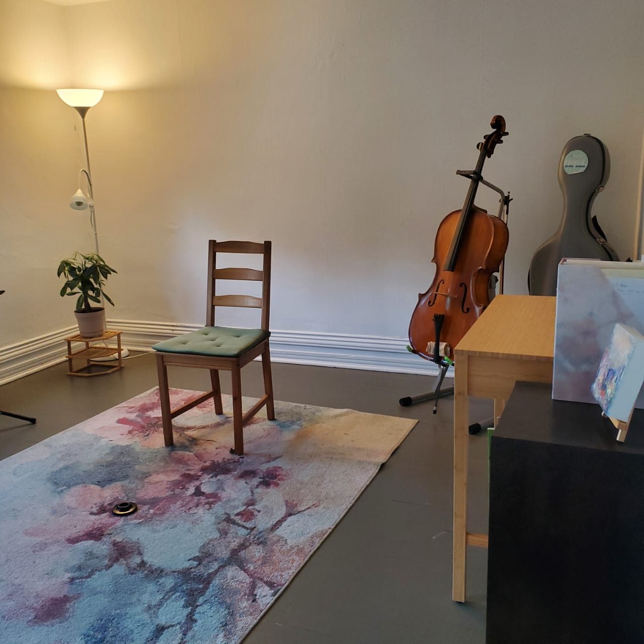 Bright rehearsal studio with a chair, cello stand, and watercolor rug