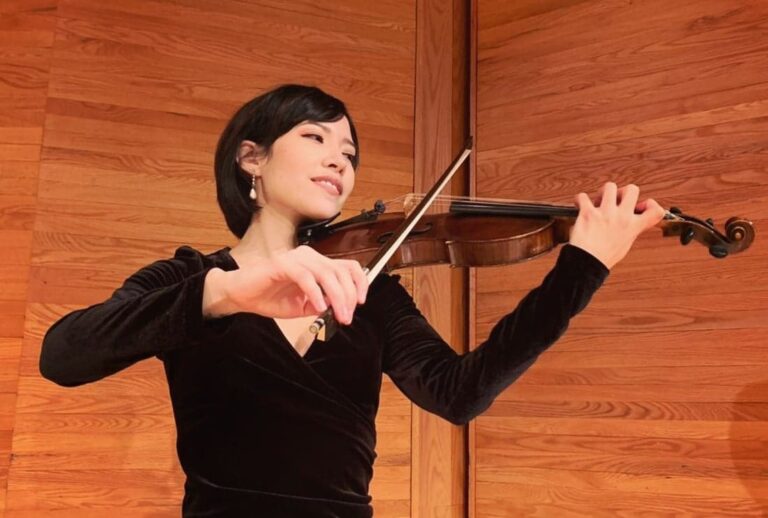 Violinist performing against a warm wood backdrop